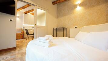 A hotel room with a large bed, a wooden ceiling, and a small desk with a chair.