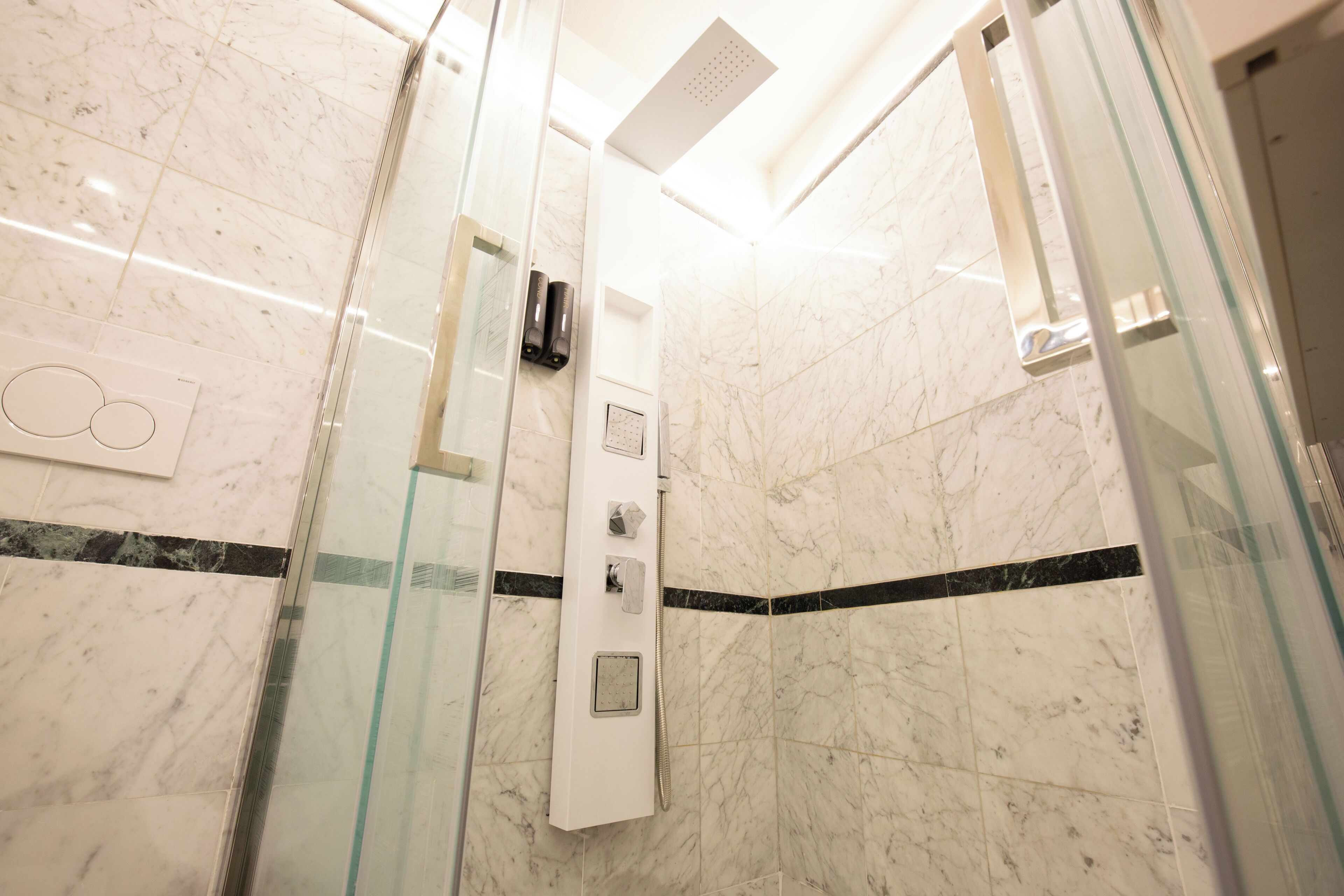 Ein modernes Badezimmer mit Duschkabine aus Glas, Marmorboden und Bedienfeld für die Dusche.