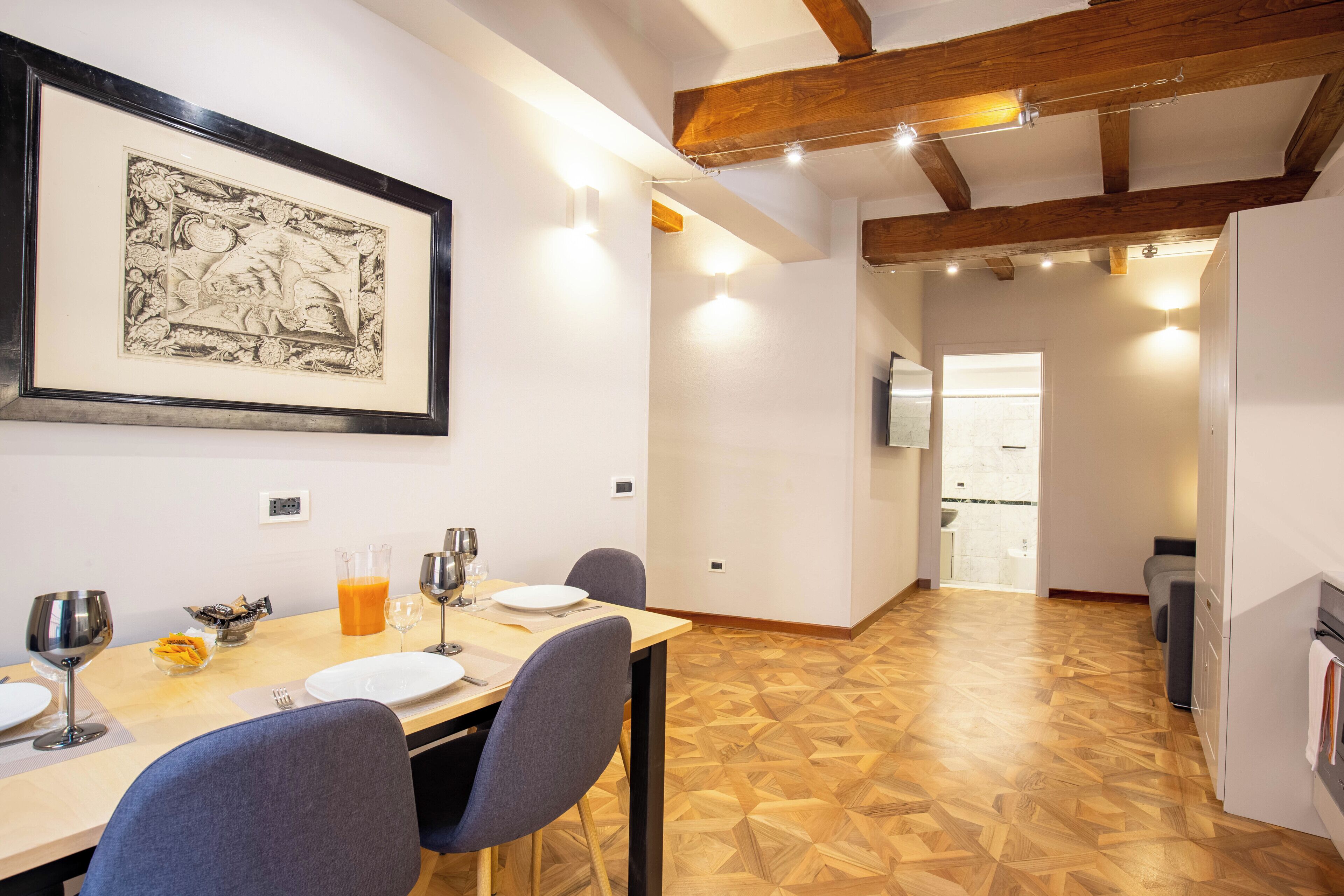 A dining area with a wooden table, chairs, and a framed artwork on the wall.