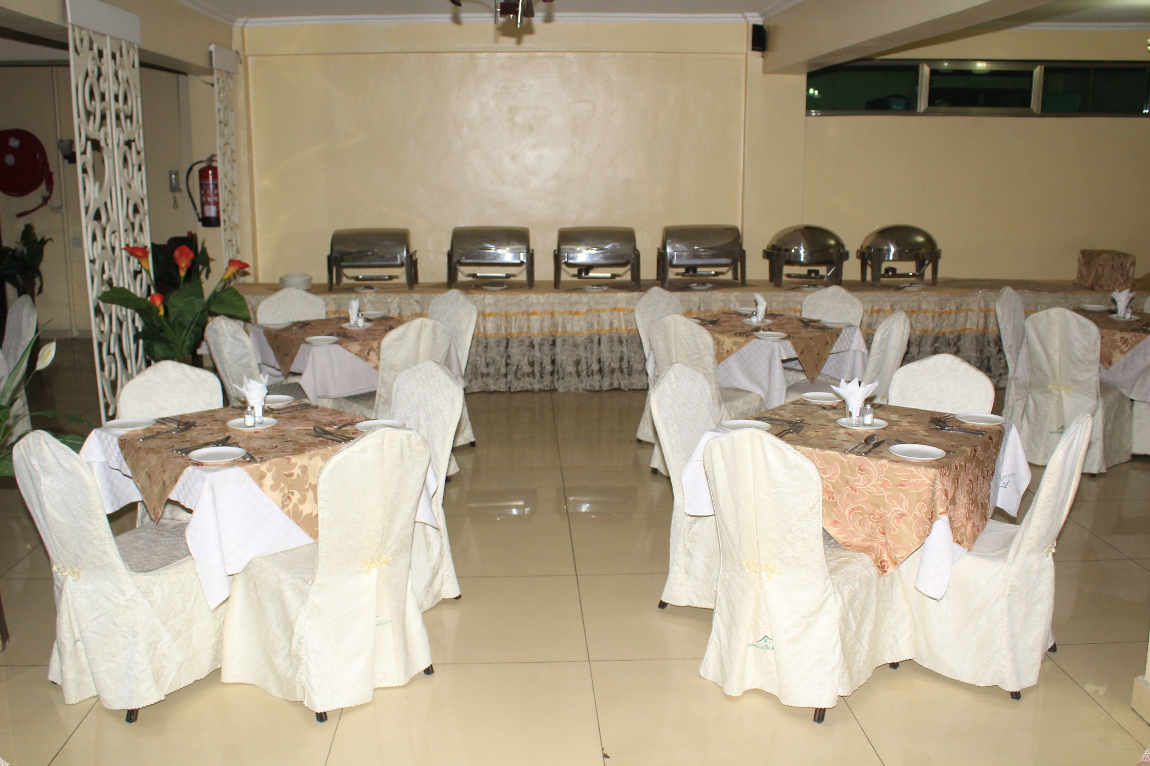 Une salle de banquet avec de nombreuses tables rondes dressées pour le repas, chacune étant agrémentée de chaises et de nappes blanches.