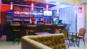 Zona de bar con mostrador, taburetes y una pantalla de televisión.