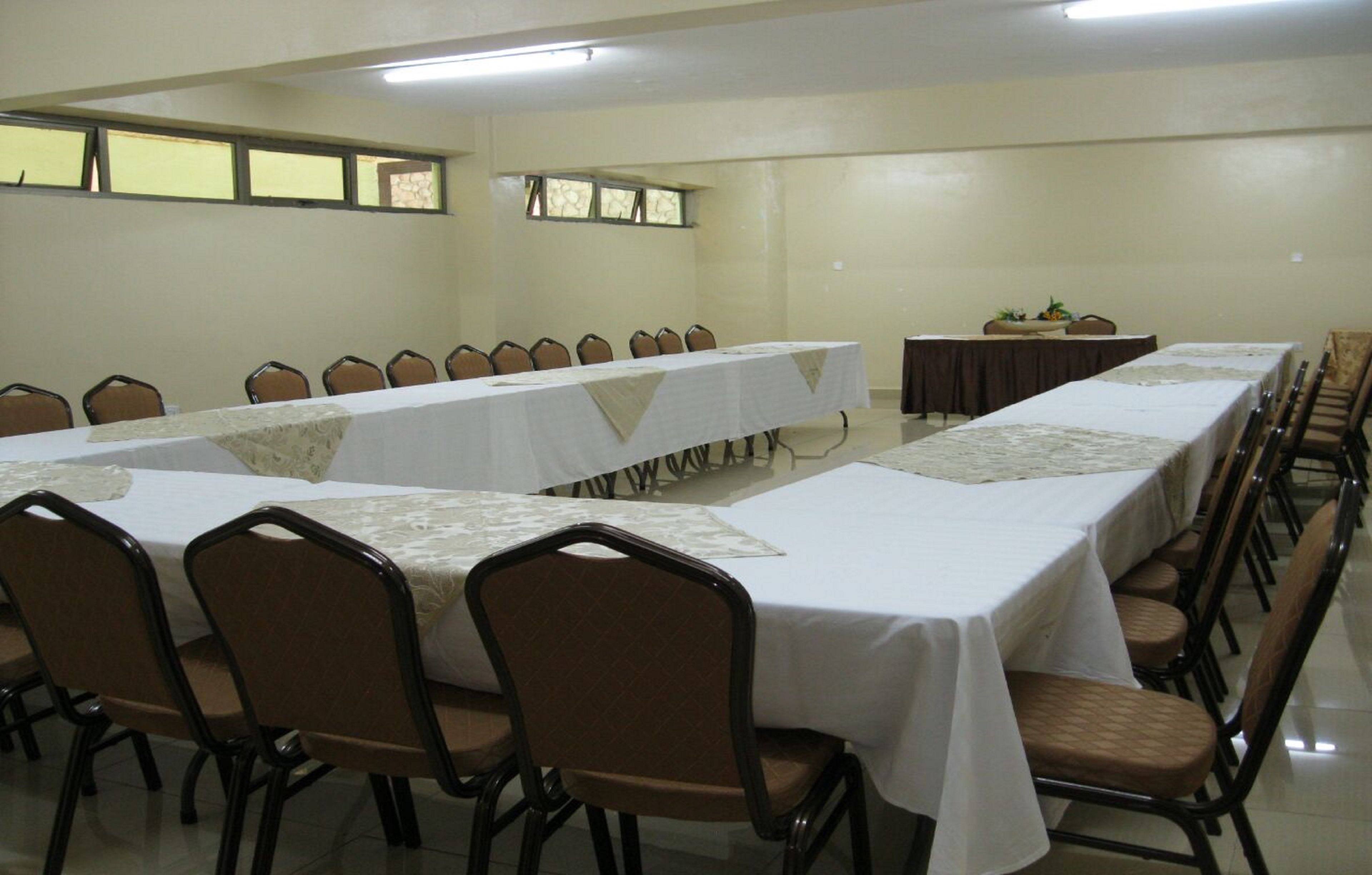 A conference room with long tables and chairs, a small stage, and a window with a view.