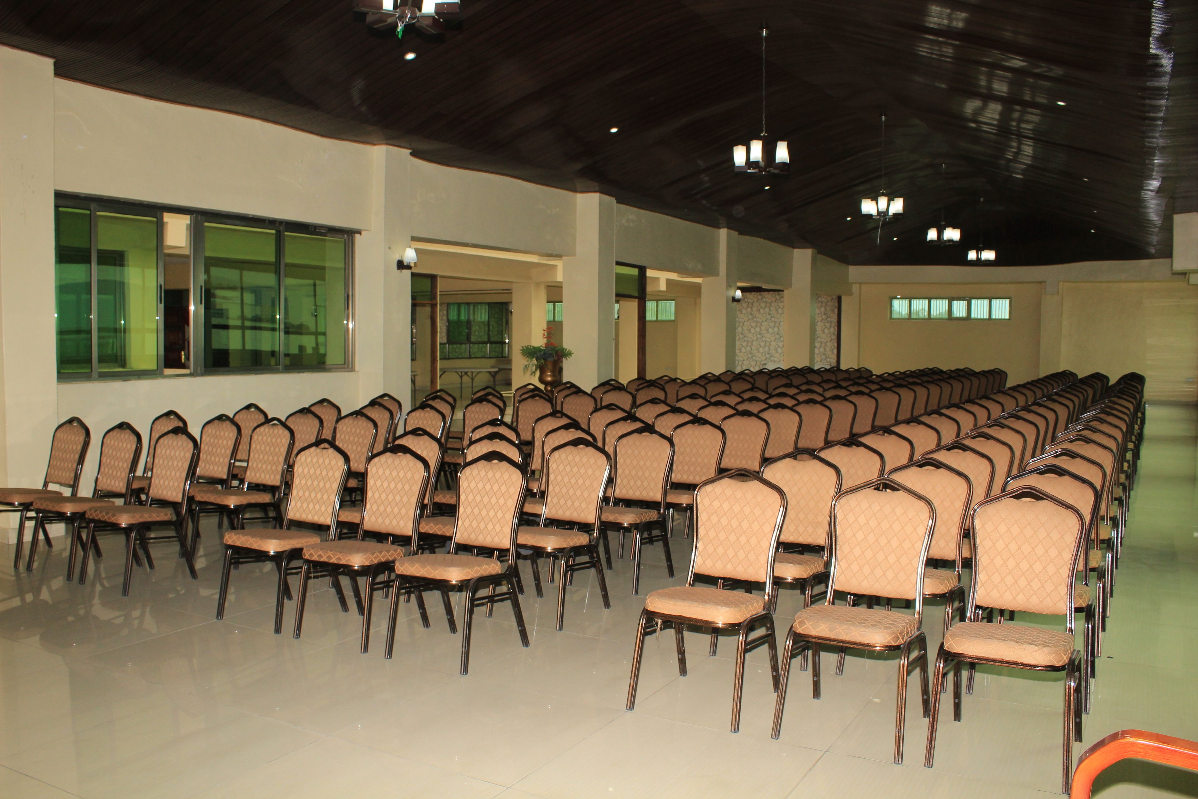 A large hall with rows of chairs and tables, high ceilings, and large windows.