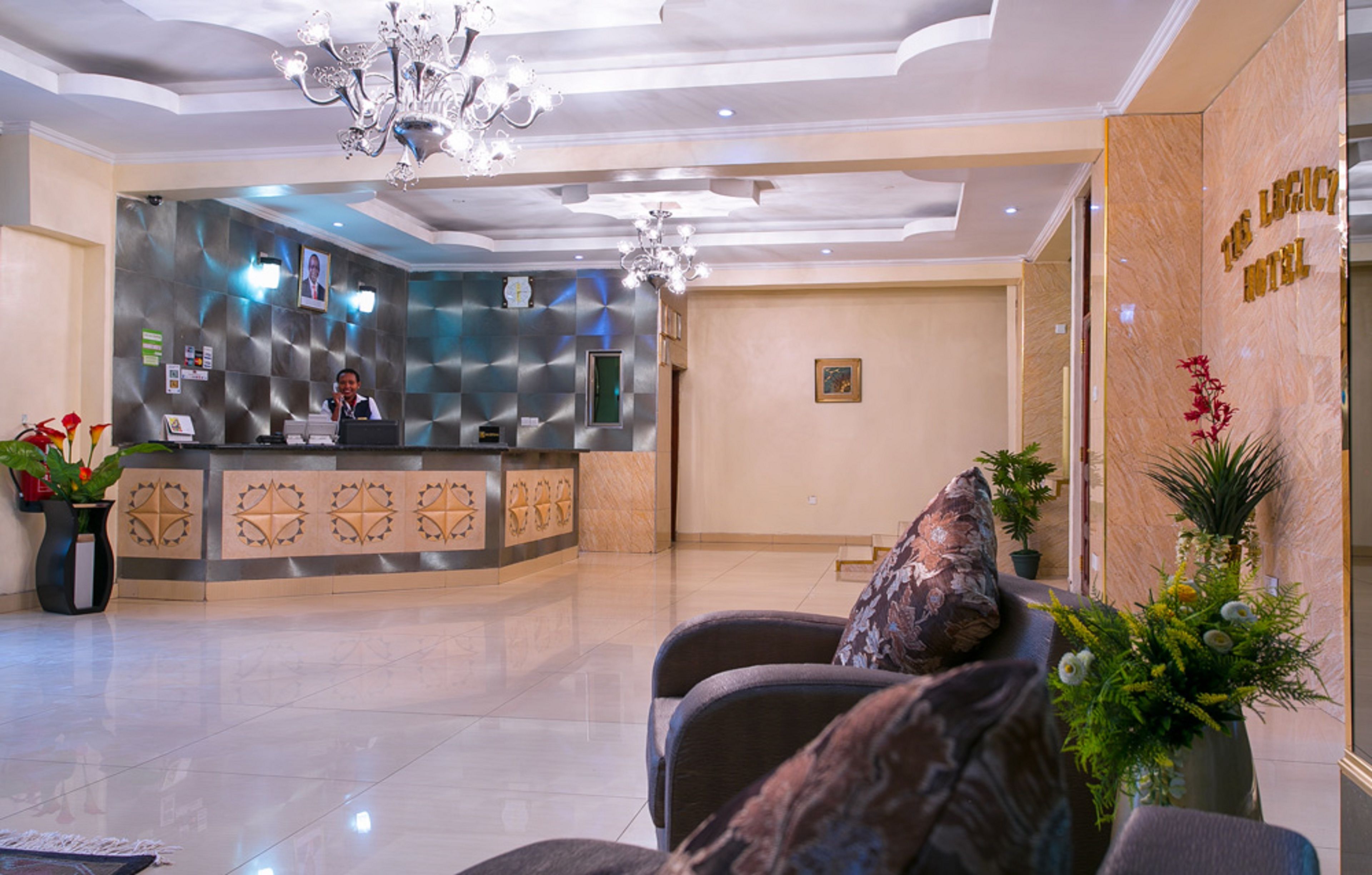 A hotel reception area with a modern design, featuring a reception desk, seating area, and a chandelier.