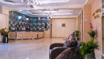 A hotel reception area with a modern design, featuring a reception desk, seating area, and a chandelier.