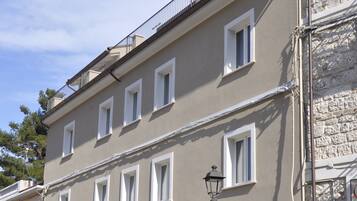 Un edificio de varios pisos con fachada de piedra, múltiples ventanas y una entrada central.