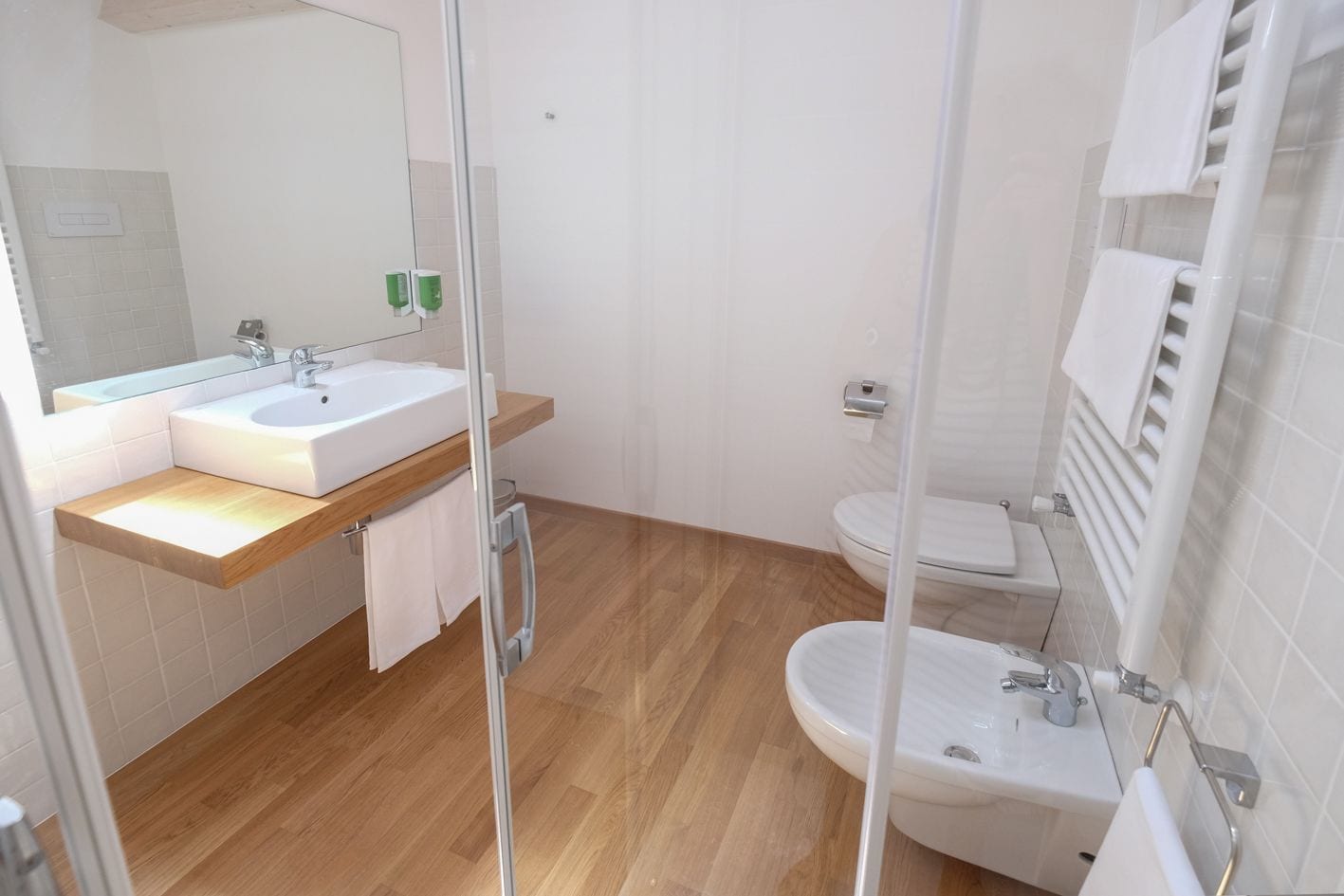 Een moderne badkamer met een wastafel, spiegel, toilet en bidet.