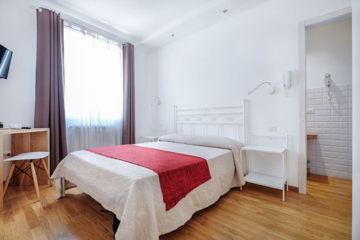 A hotel room with a bed, a desk, and a chair.