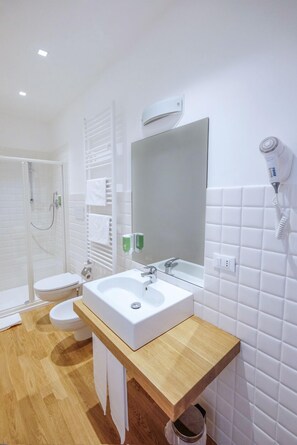 A modern bathroom with a wooden vanity, a white sink, a mirror, a hairdryer, and a shower area. - Da Oreste Affittacamere (Fara San Martino)