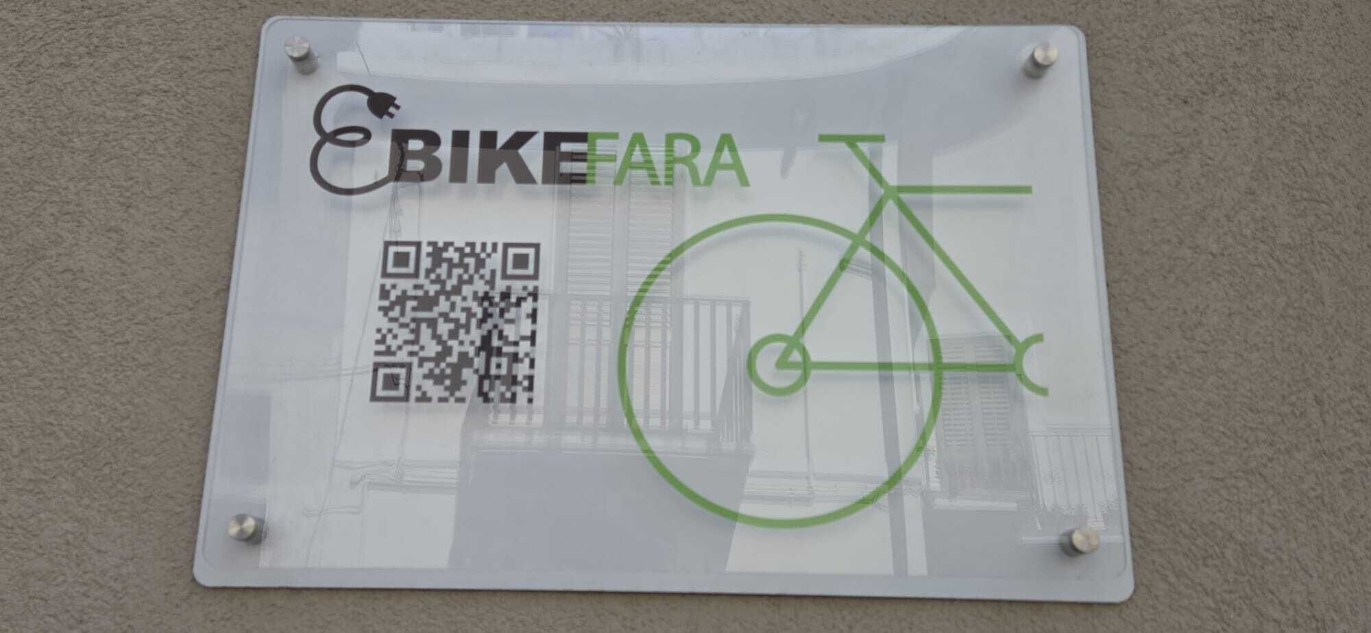 Un cartel con un código QR y un símbolo de bicicleta, sujeto a una pared.