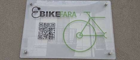 Un cartel con un código QR y un símbolo de bicicleta, sujeto a una pared.