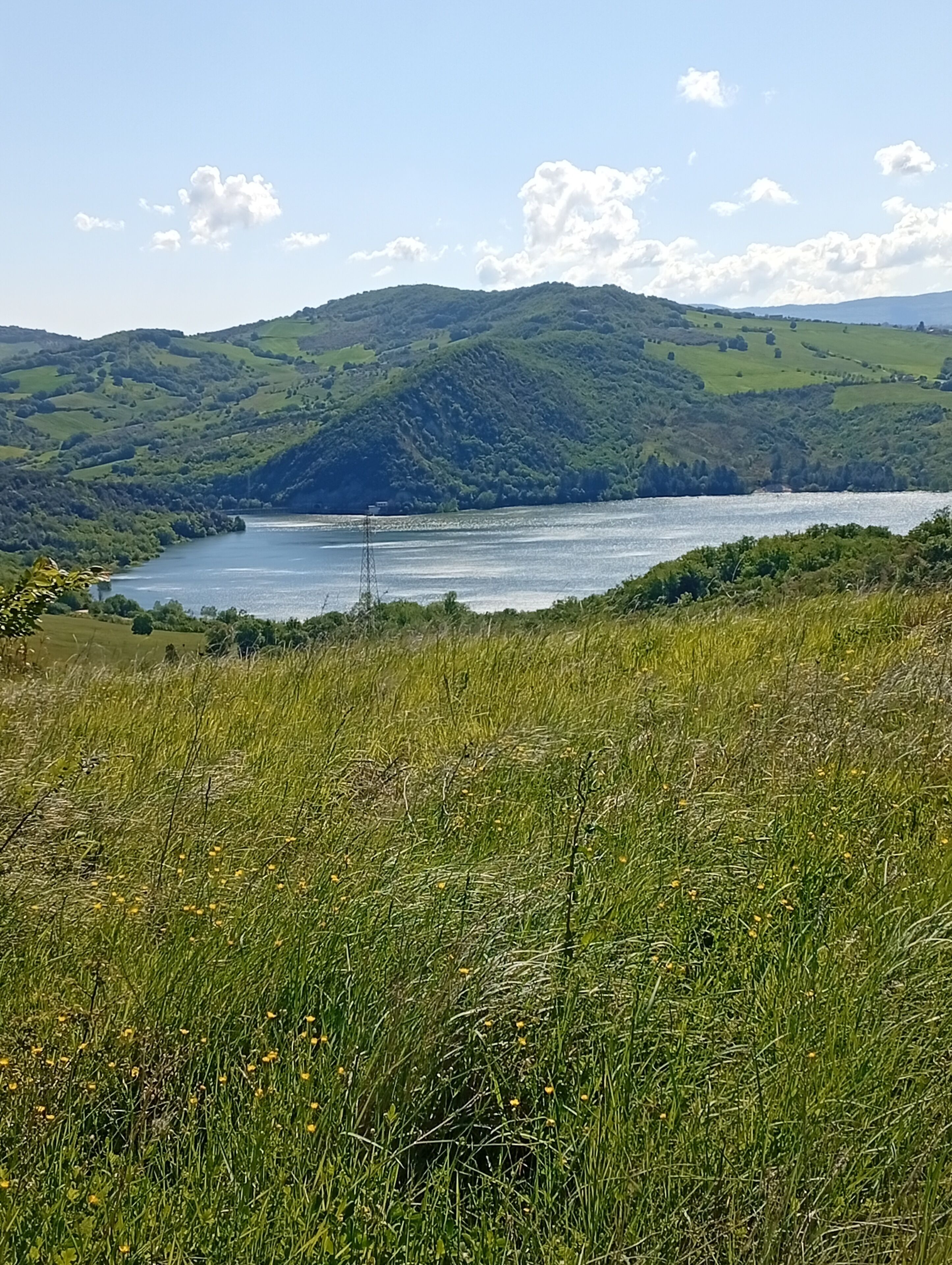 A natural landscape with a lake, hills, and a clear sky.