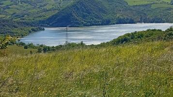 A natural landscape with a lake, hills, and a clear sky.