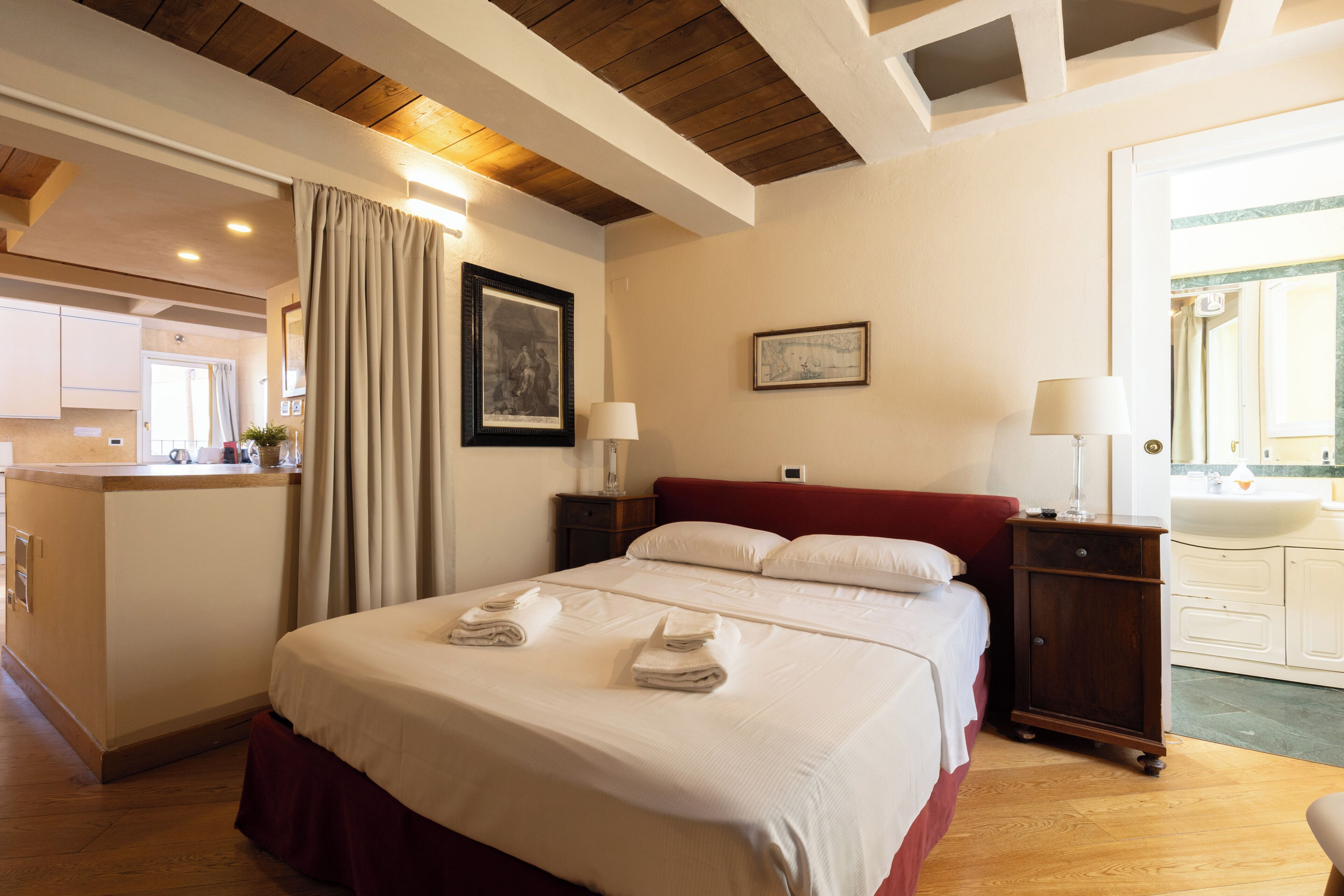 A hotel room with a bed, bedside tables, a mirror, a map on the wall, and a view of the bathroom.