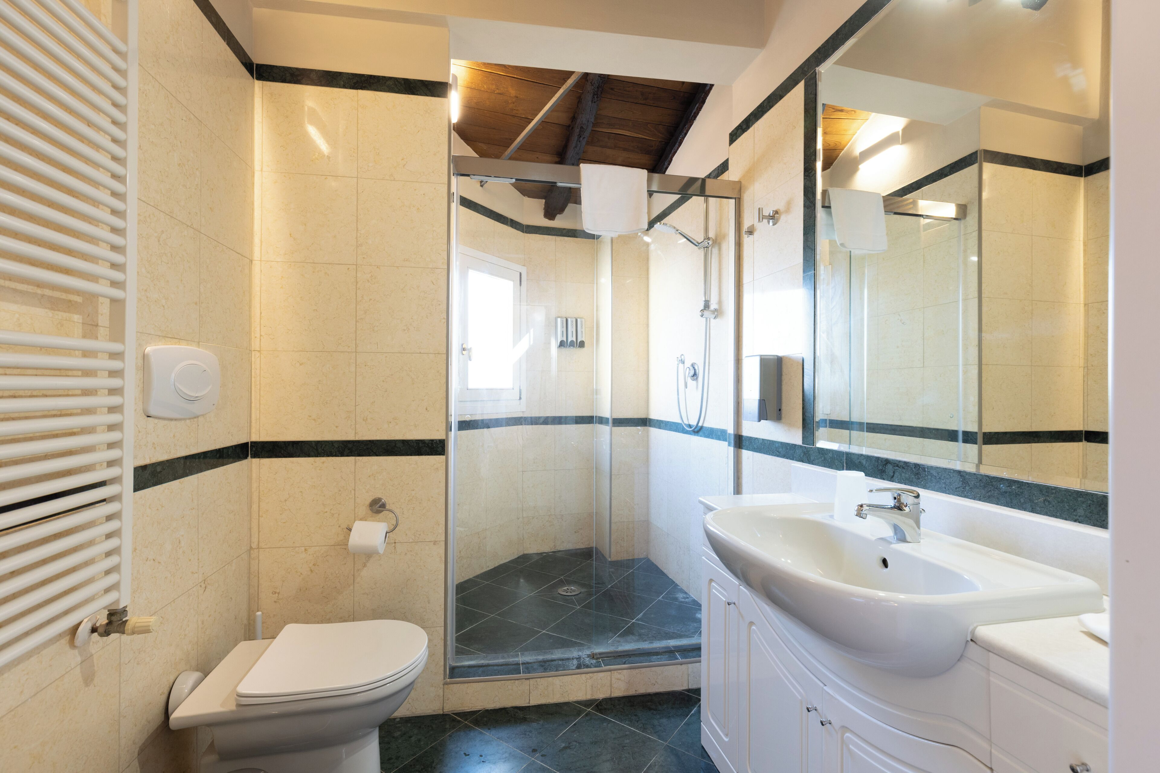 A bathroom with a toilet, a shower with glass doors, and a sink with a mirror.