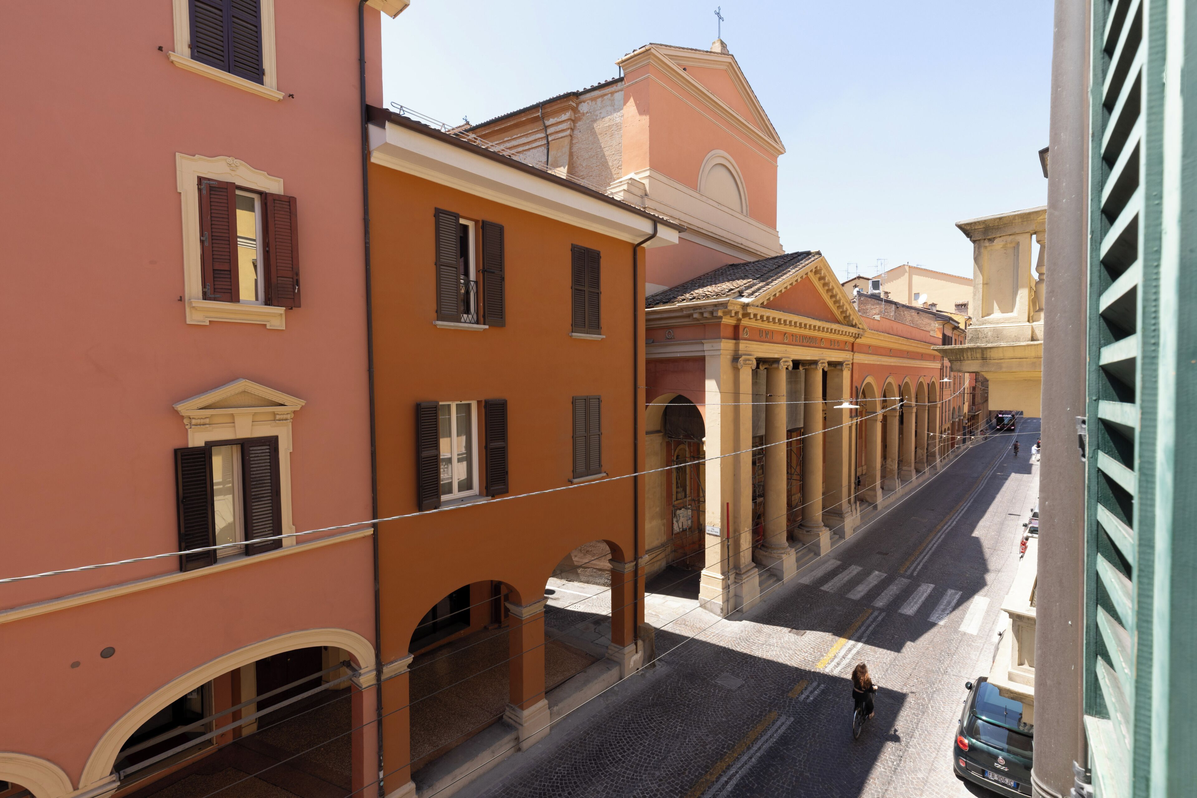 A street view with buildings featuring arched windows and a clear sky.