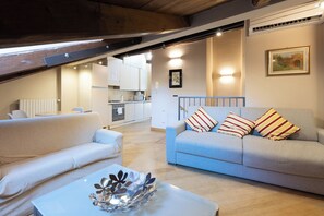 Una sala de estar moderna con un sofá, una mesa de centro y una cocina al fondo.