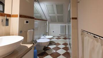 Een badkamer met een groot bad, toilet en douche.
