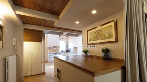 A modern kitchen with wooden cabinetry, a central island, and a dining area with white chairs.