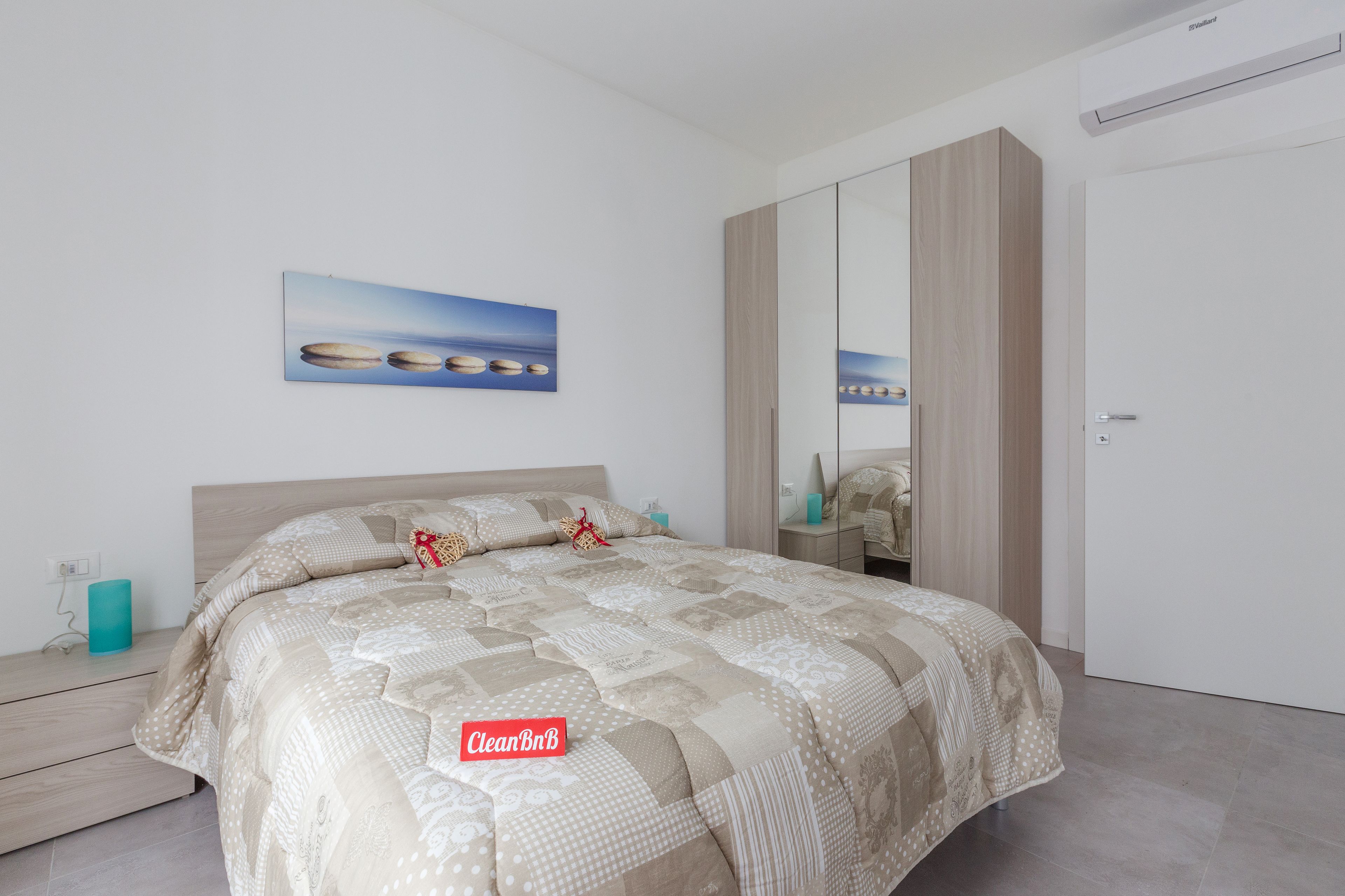 Una camera da letto moderna con un letto grande, un comodino, una cassettiera e uno specchio.