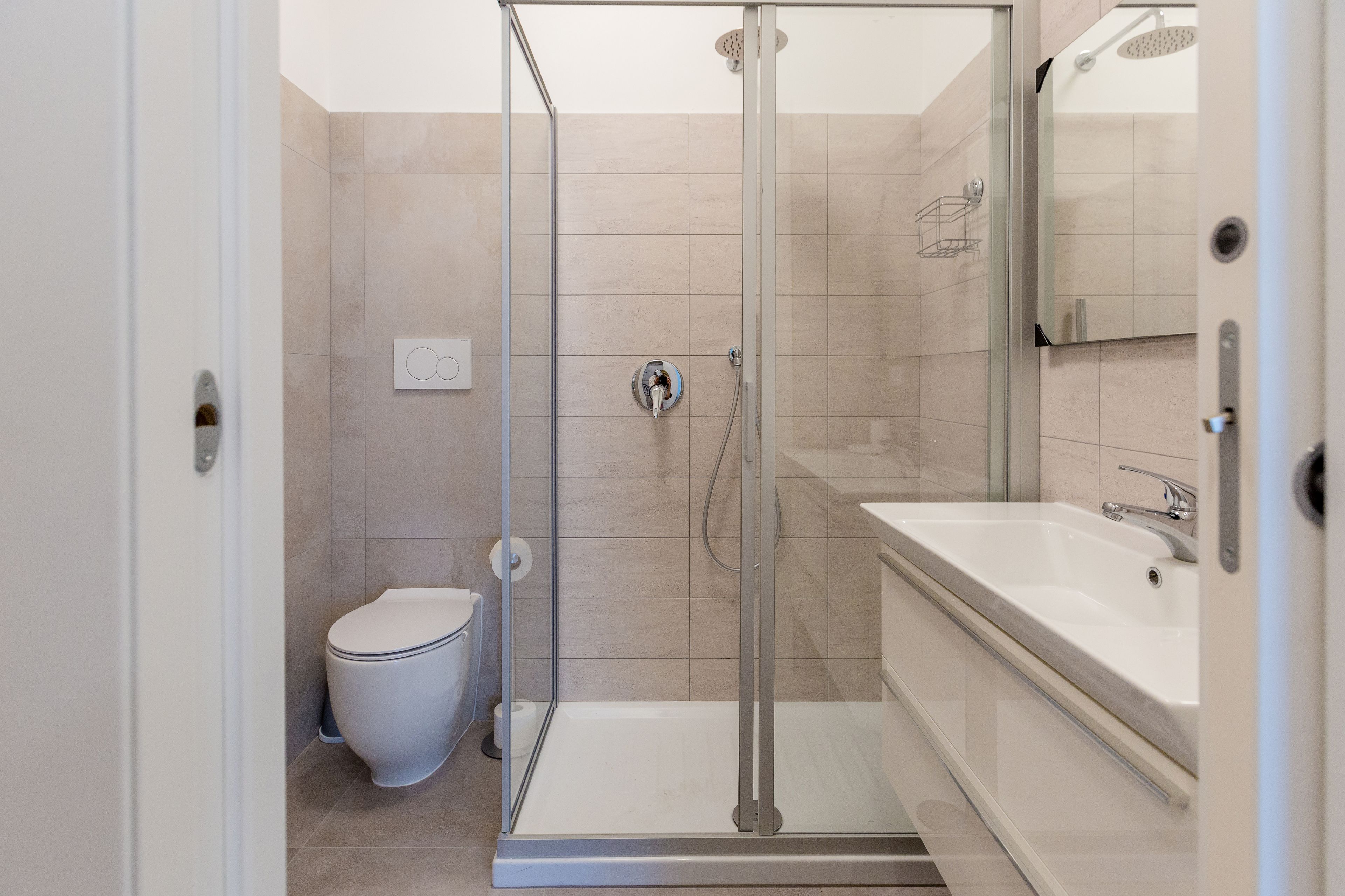Un baño moderno con ducha de vidrio, inodoro y un lavabo grande con espejo.