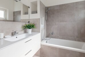 Une salle de bain moderne avec un lavabo blanc, une baignoire et une douche.