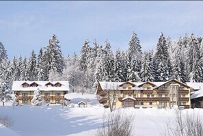 A large lodge with multiple floors and a central tower, surrounded by snow-covered trees.