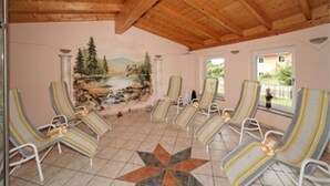 Uma sala de sol com um mural de paisagem, seis poltronas listradas e piso de azulejos.
