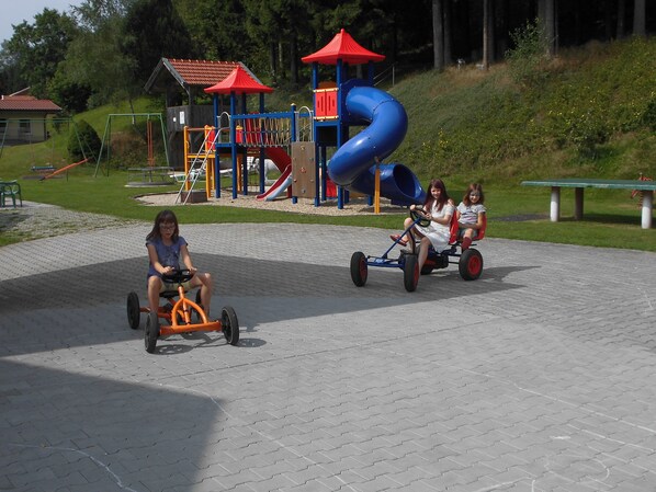 Un espacio pavimentado con un parque infantil que incluye un tobogán y estructuras para escalar.