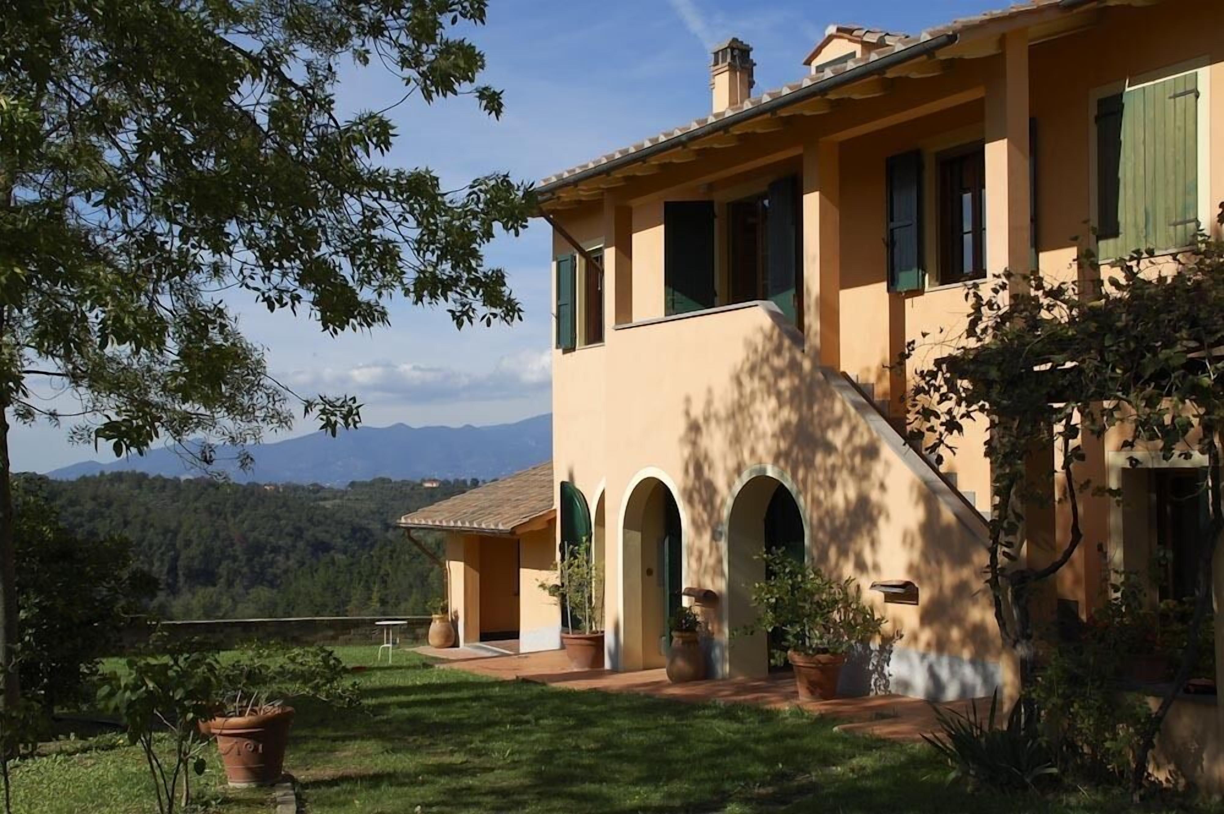 A Mediterranean-style villa with a terracotta facade, arched windows, and a lush garden.