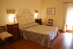 Un dormitorio con cama, dos mesitas de noche, una silla y un buró.