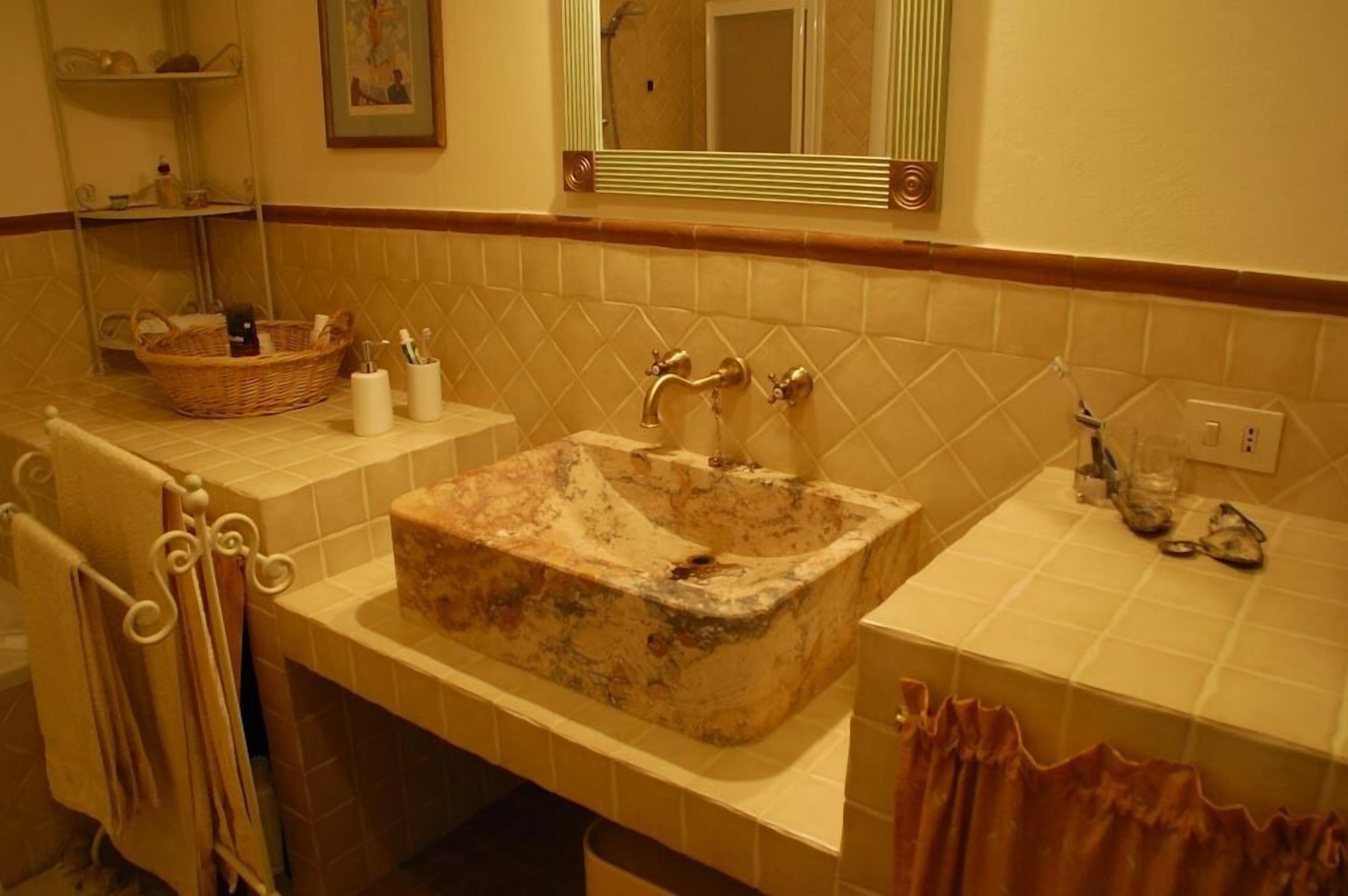 A bathroom with a marble sink, a wicker basket, and a mirror above the sink.