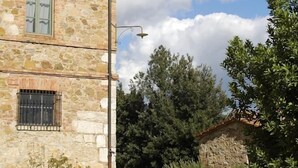 Un bâtiment en pierre avec un toit recouvert de tuiles, une fenêtre visible et un chemin qui y mène.
