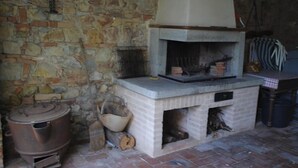 Une pièce aux murs de pierre, dotée d’un poêle à bois encastré, d’un récipient en métal et d’un seau.