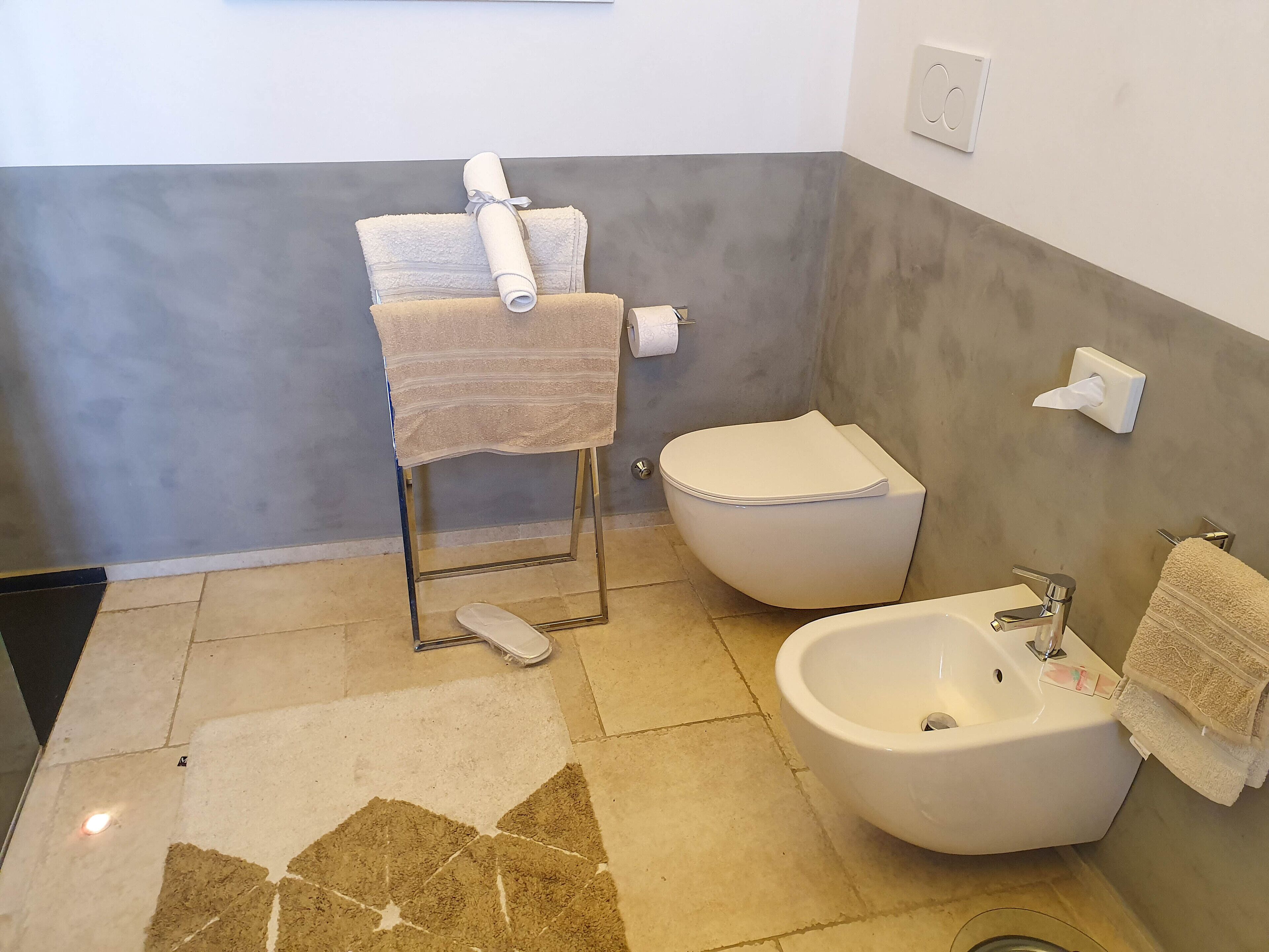 Une salle de bain comprenant des toilettes, un bidet, un lavabo et un porte-serviettes.