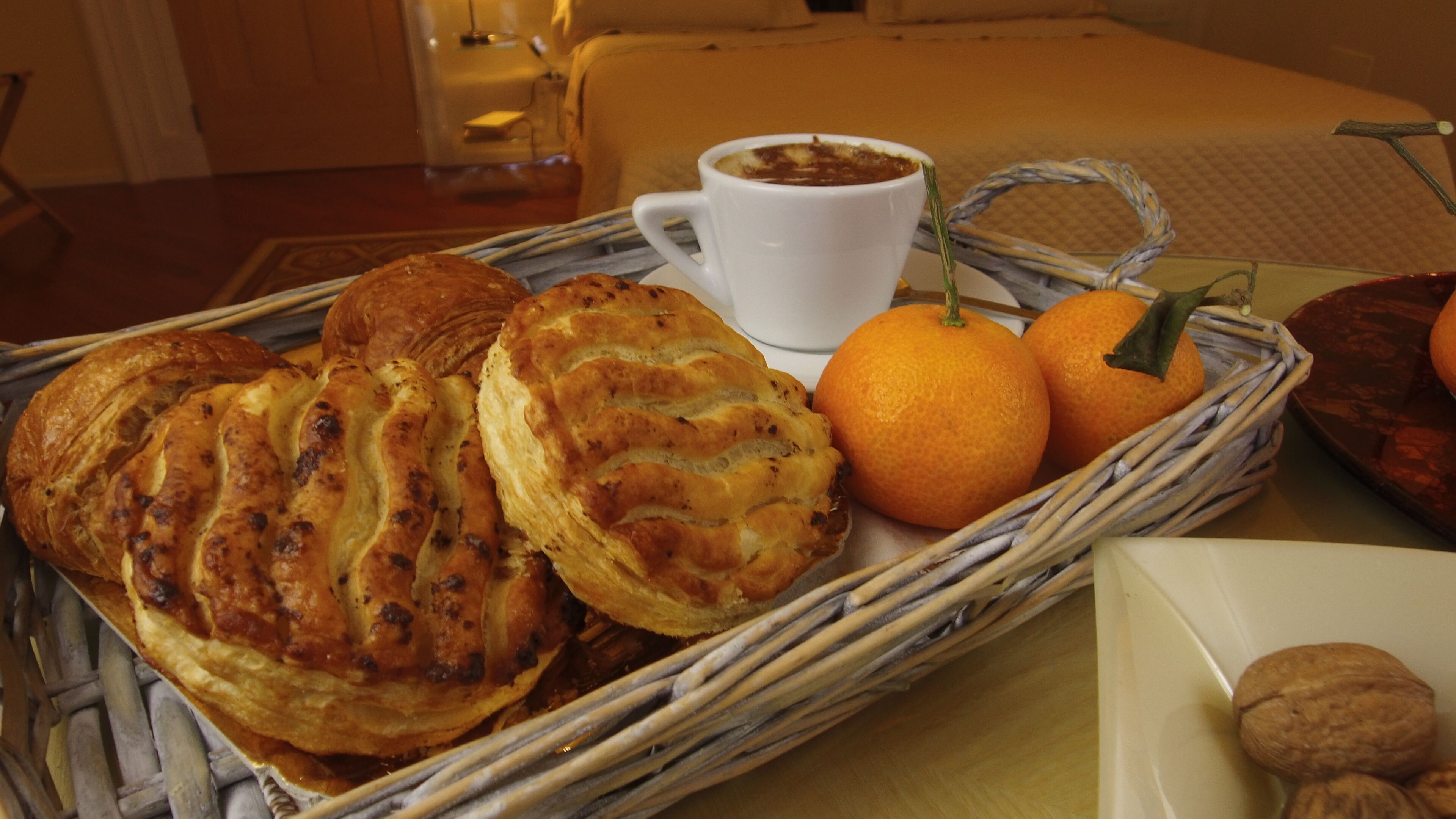 Un plateau de petit-déjeuner avec des viennoiseries, une tasse de café et des oranges, posé sur une table.