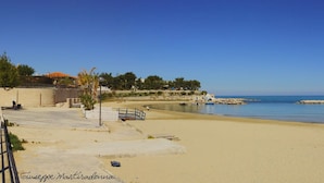 A beach with clear blue water, a sandy shore, and a few people walking. - Turenum Apartment B&B (Trani)