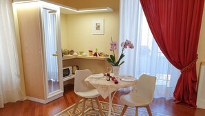 A dining area with a table set for two, a microwave, a kettle, and a potted plant. - Turenum Apartment B&B (Trani)