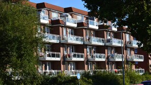 Un edificio residenziale a più piani con balconi, facciata in mattoni e un cielo azzurro intenso.