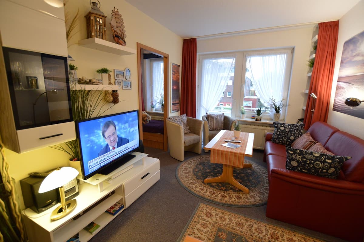 A living room with a television, sofa, armchair, and a small table.