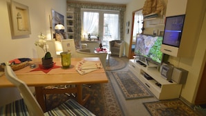 Un accogliente soggiorno con un tavolo da pranzo in legno, una televisione e un’area salotto confortevole.