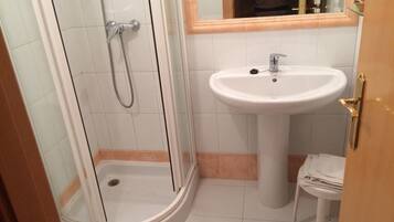 A bathroom with a glass-enclosed shower, a pedestal sink, and a toilet.