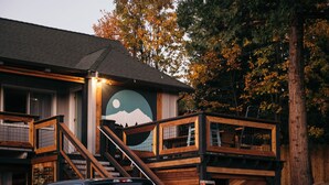 A building with a wooden staircase leading to a balcony, a mountain mural on the wall, and a truck parked in front. - Summit View Inn (Mount Shasta)