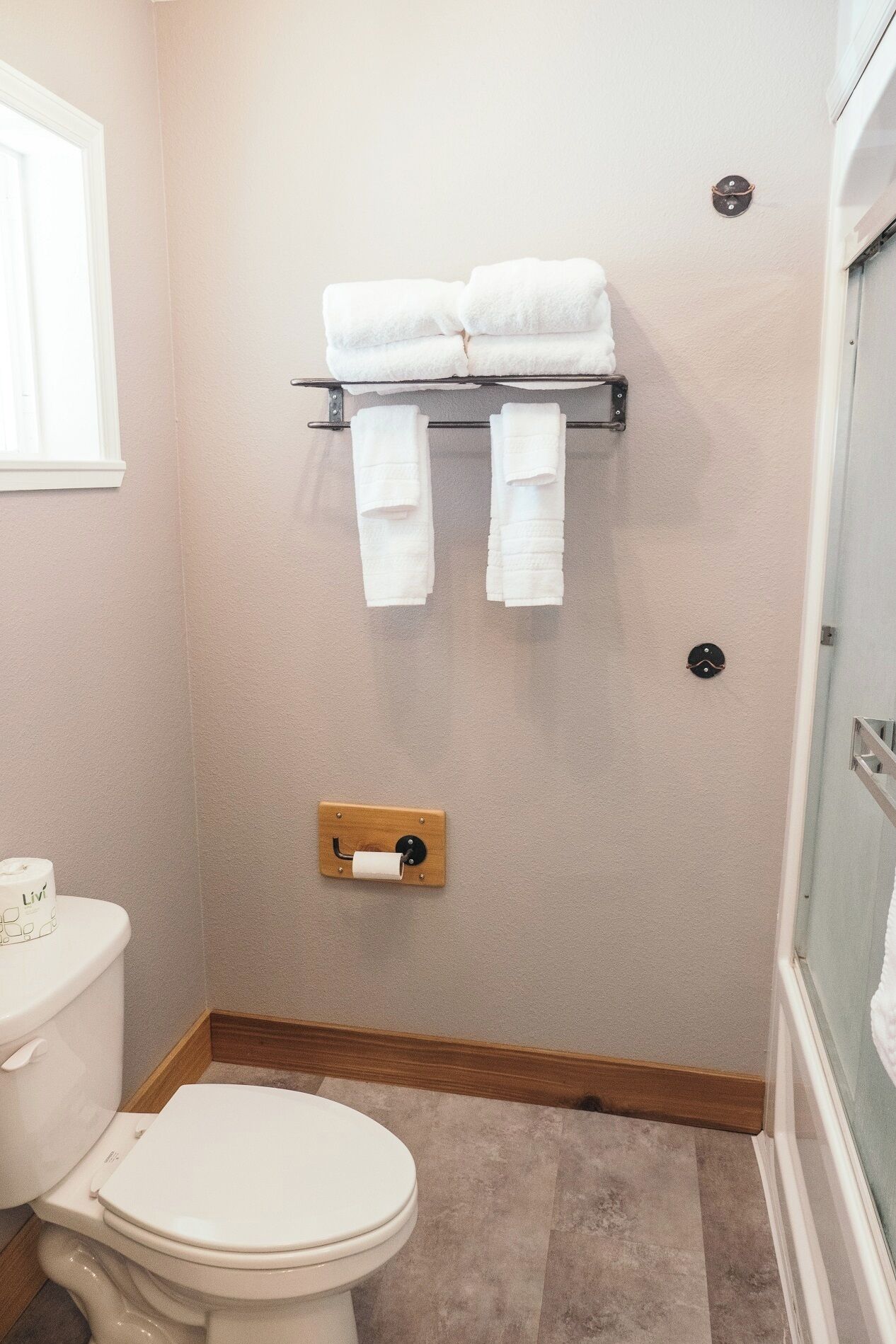 Un bagno con il water, un portasciugamani con asciugamani, un porta carta igienica e una zona doccia.