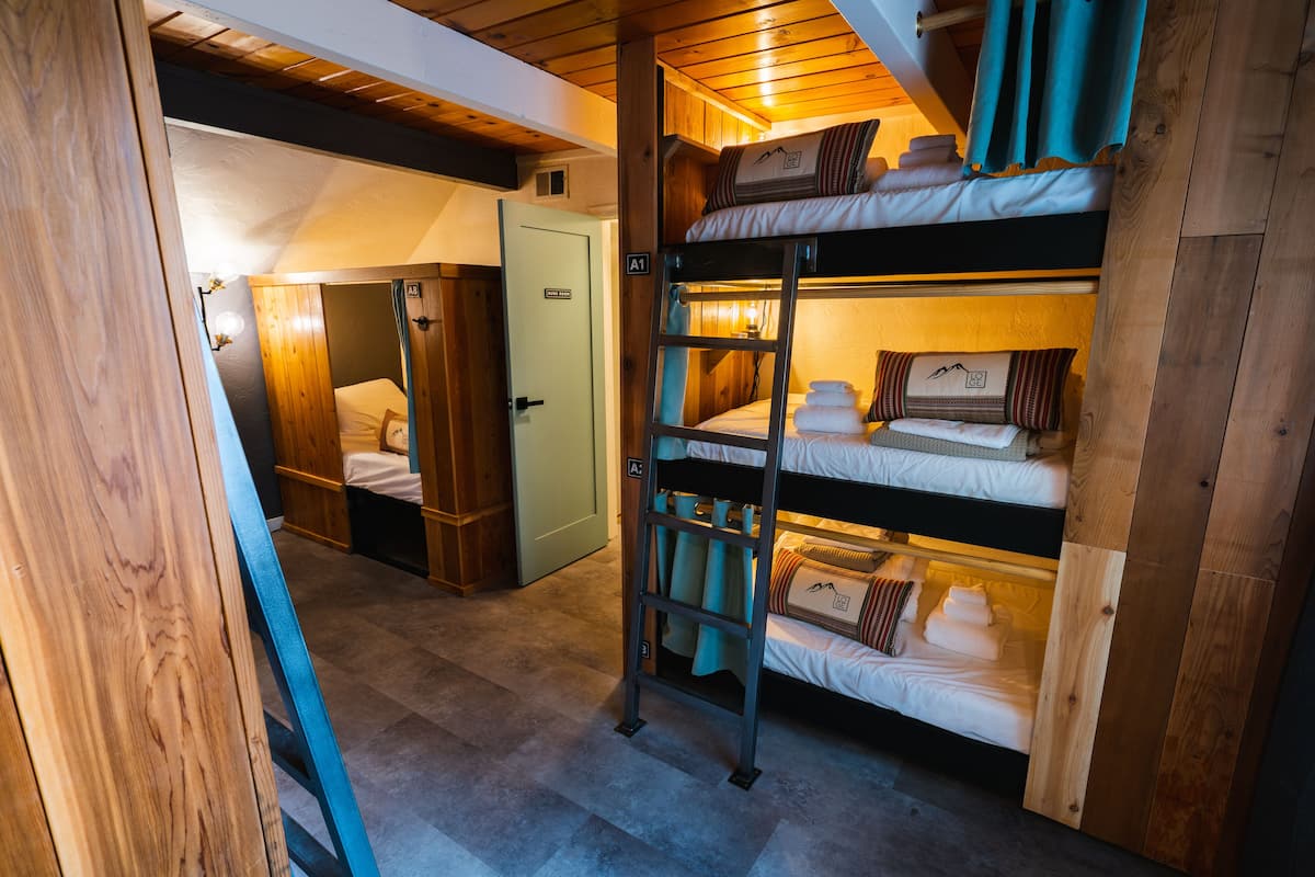 A bunk bed room with a ladder, wooden walls, and a door labeled "A1".