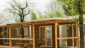 A wooden cabin with a covered porch, large sliding glass doors, and a picnic table.