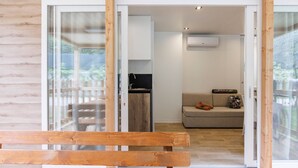 A wooden cabin with a sliding glass door leading to a kitchen and living area.