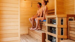 A sauna with wooden benches and a visible thermometer.