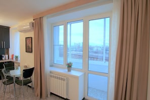 Enjoy a city view from the large window in this stylish room, featuring a dining area with a glass table and chairs.