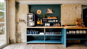 Cucina con macchina da caffè, scaffali con utensili da cucina, una pianta e vista all'esterno.